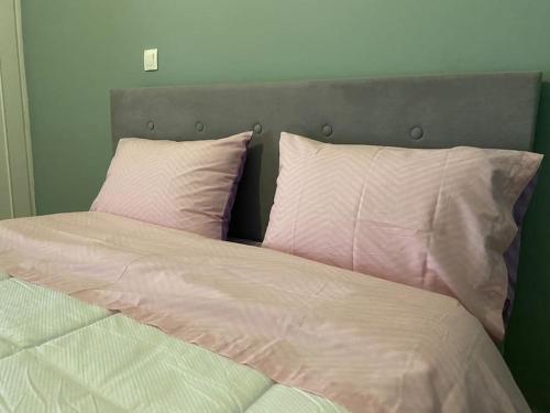 uma cama com lençóis e almofadas cor-de-rosa e brancos em Cozy new apartment near the beach em Atenas