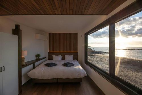 a bedroom with a bed with a view of the ocean at BLUE ARK in Izu