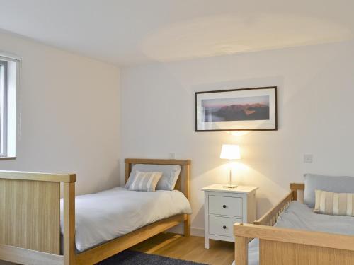 a bedroom with two beds and a lamp on a table at Bayview Cottage in Plockton