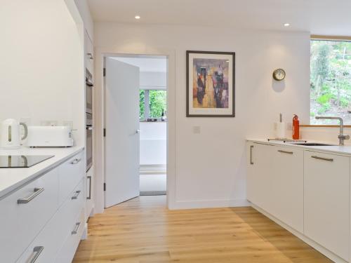 a kitchen with white cabinets and a wooden floor at Bayview Cottage in Plockton