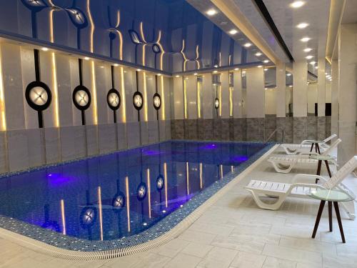 a large swimming pool with clocks on the wall at Chinor Hotel Fergana in Fergana