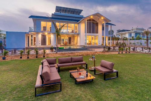 a house with a lawn with furniture in front of it at StayVista at The Francolin Farm with Free Breakfast, Infinity Pool & Jacuzzi in Sohna