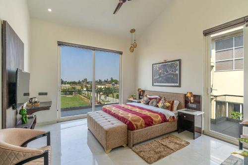 a bedroom with a bed and a large window at StayVista at The Francolin Farm with Free Breakfast, Infinity Pool & Jacuzzi in Sohna