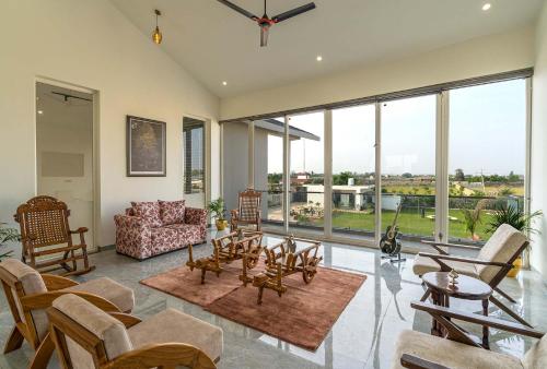 a living room filled with furniture and a large window at StayVista at The Francolin Farm with Free Breakfast, Infinity Pool & Jacuzzi in Sohna