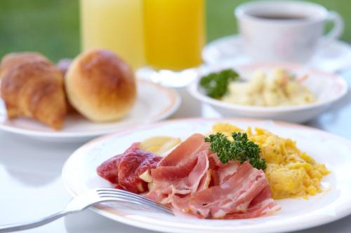 a table with plates of breakfast foods and a fork at Pacific Hotel Okinawa in Naha