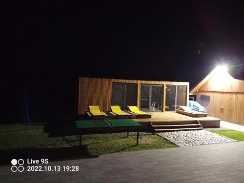 a group of chairs sitting on a deck at night at Szklane Domy Roztocze 2 in Bondyrz