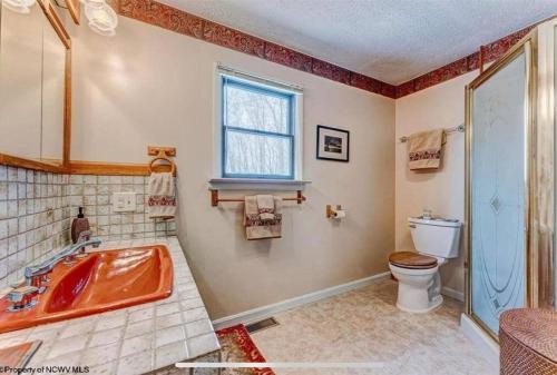 een badkamer met een bad, een toilet en een raam bij 3 Bedroom Cabin at Alpine Lake, near Deep Creek-WISP Resort in Terra Alta