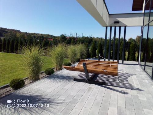 a wooden bench sitting on a patio next to a building at Szklane Domy Roztocze 2 in Bondyrz