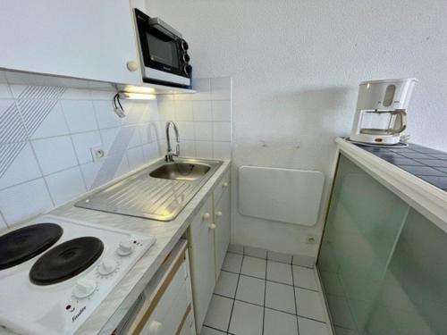 une petite cuisine avec un évier et un micro-ondes dans l'établissement Quiberon - Appartement 2 pièces - Terrasse - Parking - Animaux admis - FR-1-478-106, à Quiberon