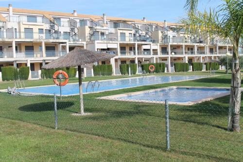 uma piscina com um guarda-sol ao lado de um edifício em Appartement tout confort, Rez-de chaussée,3 chambres, 2 salles de bain em Sant Jordi