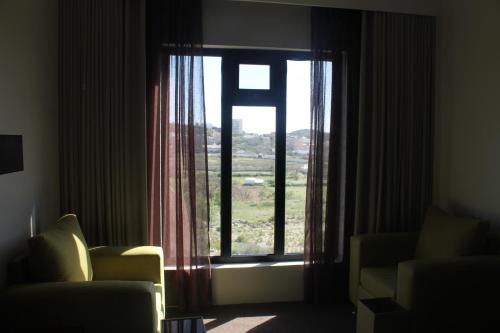a room with a window with a couch and a chair at High Village Hotel in Al Namas