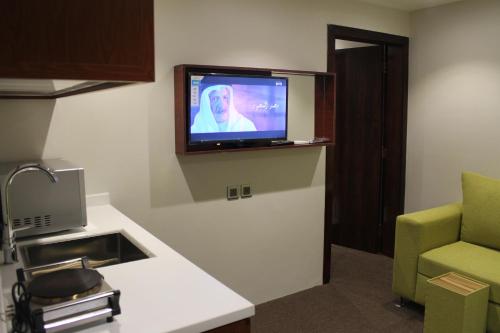 a room with a tv on a wall with a couch at High Village Hotel in Al Namas