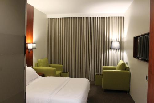 una camera d'albergo con un letto e due sedie di فندق القرية العالية - هاي فيليج هوتيل High village Hotel a Sagrit