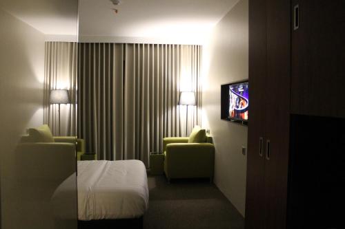 a hotel room with a bed and two chairs and a television at High Village Hotel in Al Namas