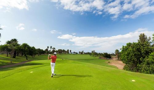 Ein Mann, der einen Golfklub auf einem Golfplatz schwingt. in der Unterkunft Abades Chalet in La Listada