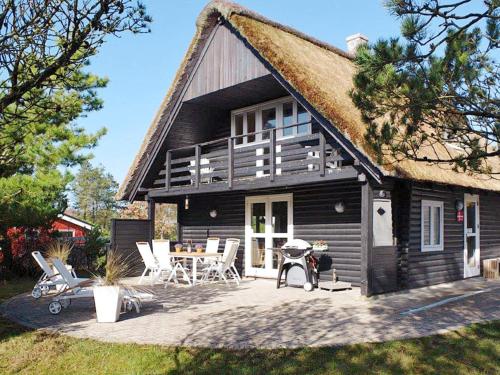 a black house with a patio and a table and chairs at 6 person holiday home in R m in Vesterhede