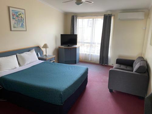 Habitación de hotel con cama y sofá en Orbost Country Man Motor Inn, en Orbost
