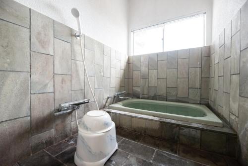 a bathroom with a tub with a toilet and a window at BLUE MOON in Kawazu
