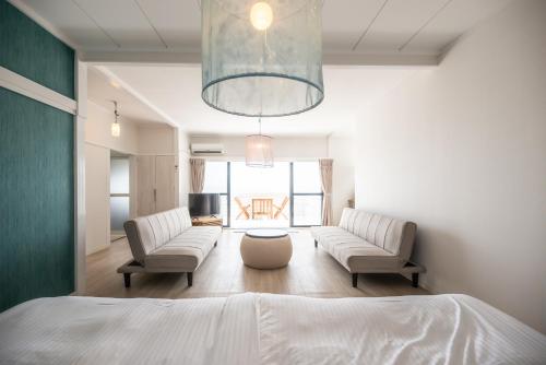 a bedroom with a bed and two chairs and a living room at BLUE MOON in Kawazu