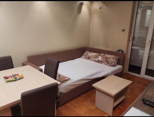 ein kleines Zimmer mit einem Bett und zwei Tischen in der Unterkunft Apartment Spens in Novi Sad