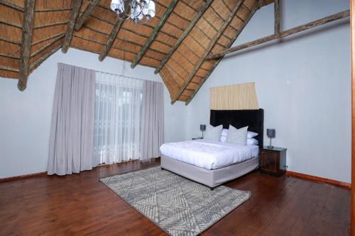 um quarto com uma cama branca e piso em madeira em Charming Country Villa Sandton with Back Up Power & Water em Joanesburgo