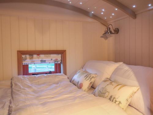 a bed with white sheets and pillows in a room at Bonnie's Shepherds Hut in Nottingham