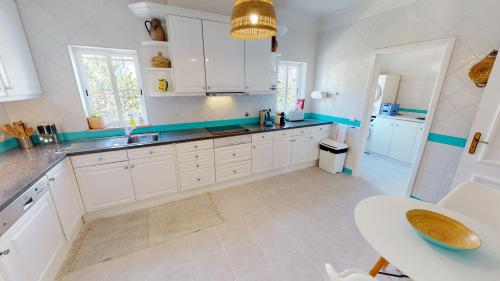 a kitchen with white cabinets and a sink and a table at Villa Sunset,sleeps 9,heatable pool,walk to marina in Vilamoura