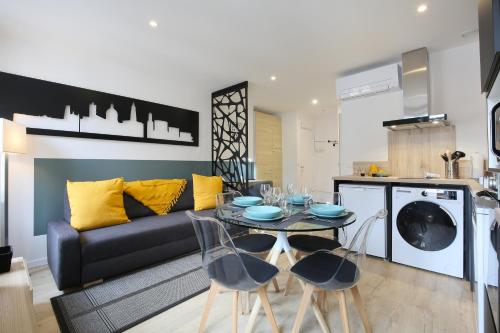 - un salon avec un canapé noir, une table et des chaises dans l'établissement expat renting - Entre Piment & Violette - Saint Michel, à Toulouse