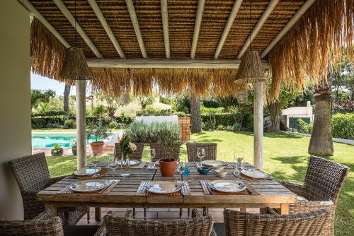 a wooden table and chairs under a pergola at Villa Sunset,sleeps 9,heatable pool,walk to marina in Vilamoura