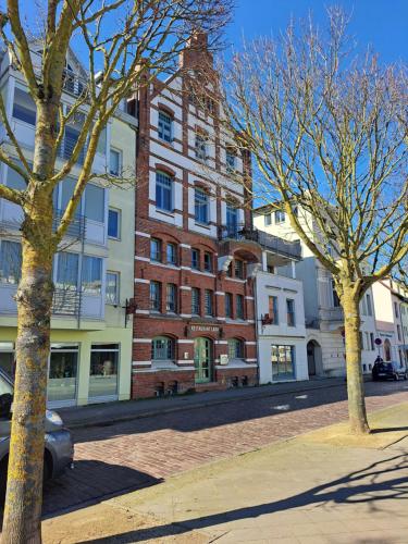 a large brick building on a city street with trees at Urige Ferienwohnung im Hafen Stralsunds in Stralsund