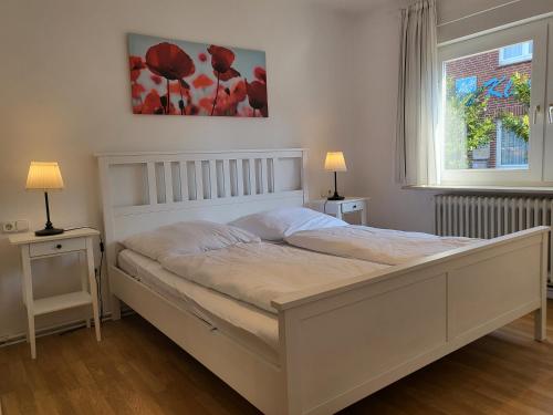 a white bed in a bedroom with two tables and a window at Ferienhaus Op de Diek in Ording
