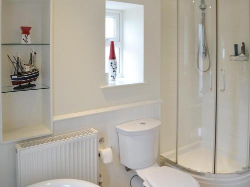 a white bathroom with a toilet and a shower at Sandpipers in Padstow