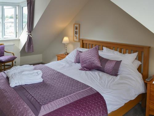 a bed with purple and white sheets and pillows at Sandpipers in Padstow