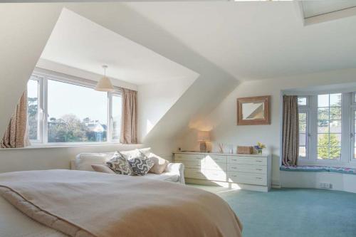 a bedroom with a bed and a dresser and windows at Compass Cottage in Abersoch