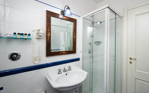 y baño con lavabo y ducha acristalada. en Chiaja Hotel de Charme en Nápoles