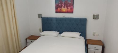 a bedroom with a large bed with a blue headboard at Apartment Rina in Sarandë