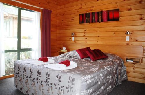 1 dormitorio con 1 cama con 2 toallas en The Chalets Motel, en Hanmer Springs