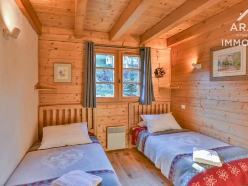 dwa łóżka w drewnianym domku z oknem w obiekcie Chalet Le Grand-Bornand, 8 pièces, 11 personnes - FR-1-391-22 w mieście Le Grand-Bornand