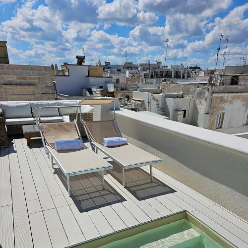 a balcony with two chairs and a pool on a roof at IL GELSO BIANCO Luxury apartments in Polignano a Mare