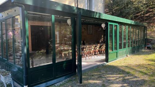a green house with tables and chairs in a yard at La Villa del Lago in Ghirla