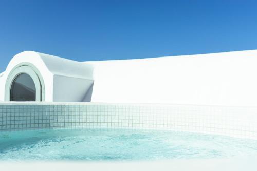 una vasca da bagno con una piscina d'acqua accanto a un edificio di Astro Palace Hotel & Suites a Firà