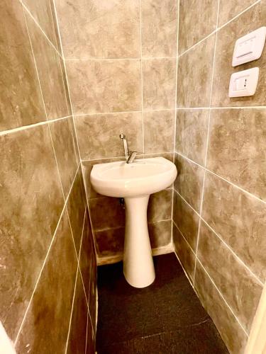 a bathroom with a white sink in a tiled wall at RoadHouse - Petra in Wadi Musa
