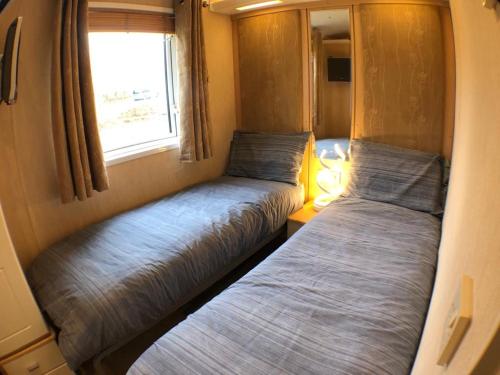 2 Betten in einem kleinen Zimmer mit Fenster in der Unterkunft Whitwell and Reepham Station - GEORGIE in Reepham