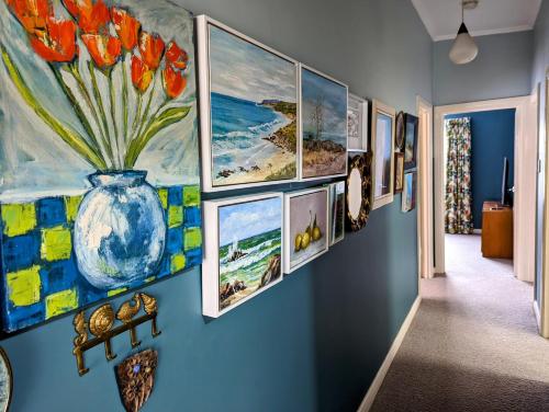 a hallway with a bunch of paintings on a wall at Jamaica Mid-Century in Seaton