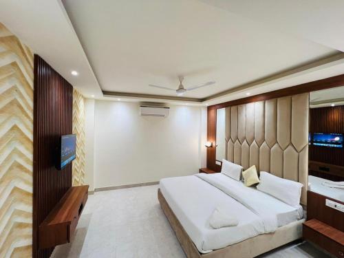 a bedroom with a large white bed and a tv at Hotel RIVERB in New Delhi