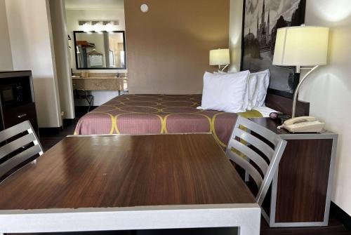 a hotel room with a bed and a desk with a phone at Super 8 by Wyndham Slidell in Slidell