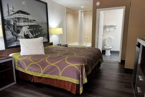 a hotel room with a bed and a bathroom at Super 8 by Wyndham Slidell in Slidell