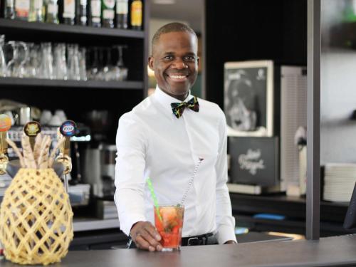 Um homem atrás de um bar a beber. em ibis Styles Evry Courcouronnes Hotel and Events em Courcouronnes