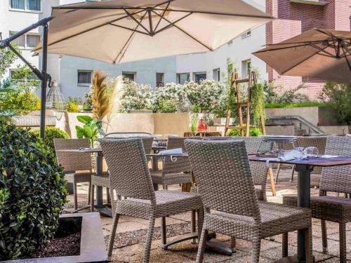 un patio al aire libre con mesas, sillas y una sombrilla en ibis Styles Evry Courcouronnes Hotel and Events, en Courcouronnes