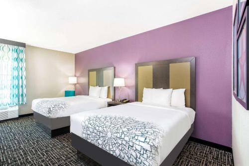 um quarto de hotel com duas camas e paredes roxas em La Quinta by Wyndham Hillsboro em Hillsboro
